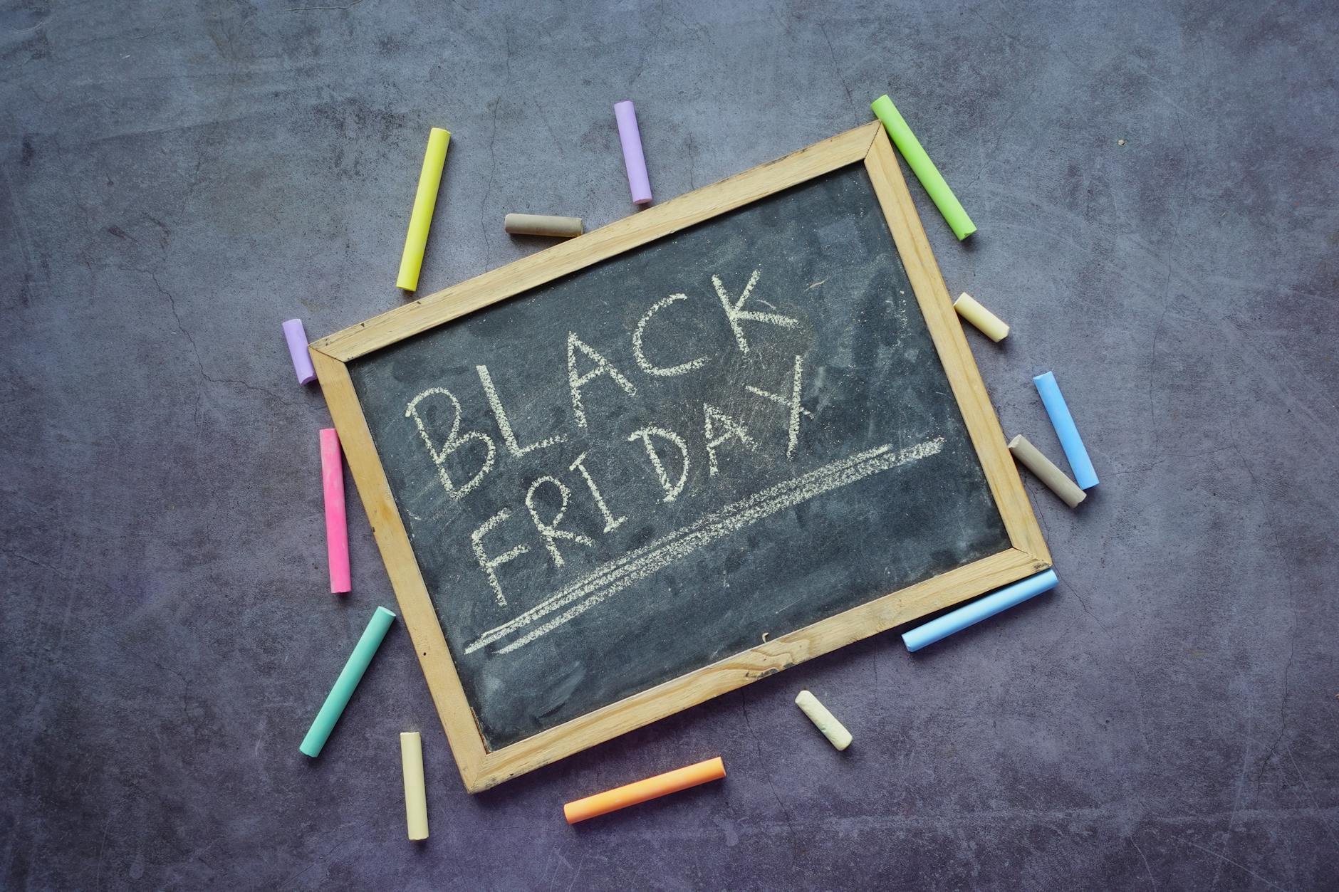 A chalkboard with 'Black Friday' written, surrounded by colorful chalks, perfect for promotions.