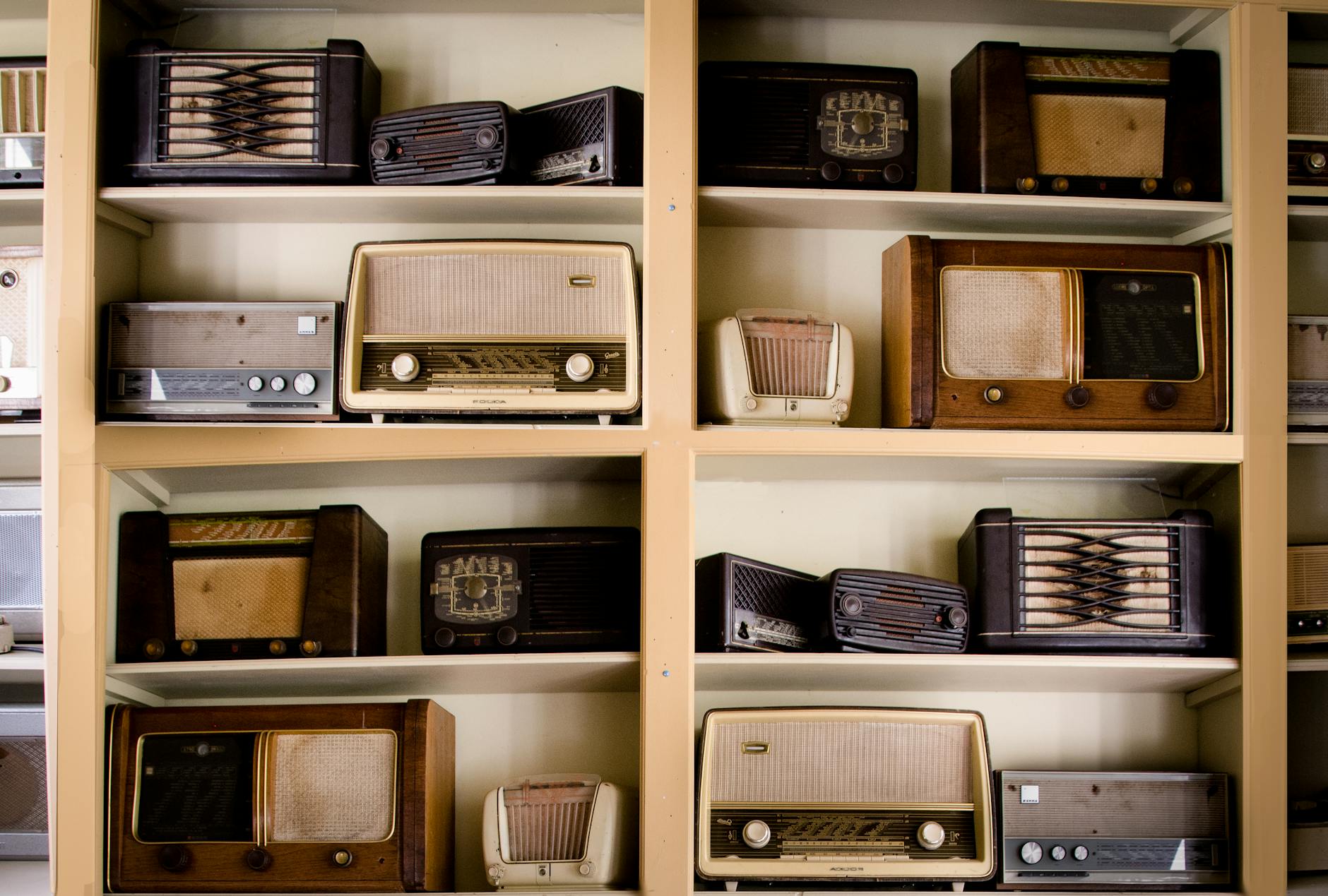 A curated collection of vintage radios displayed on shelves in an antique store, showcasing retro designs.