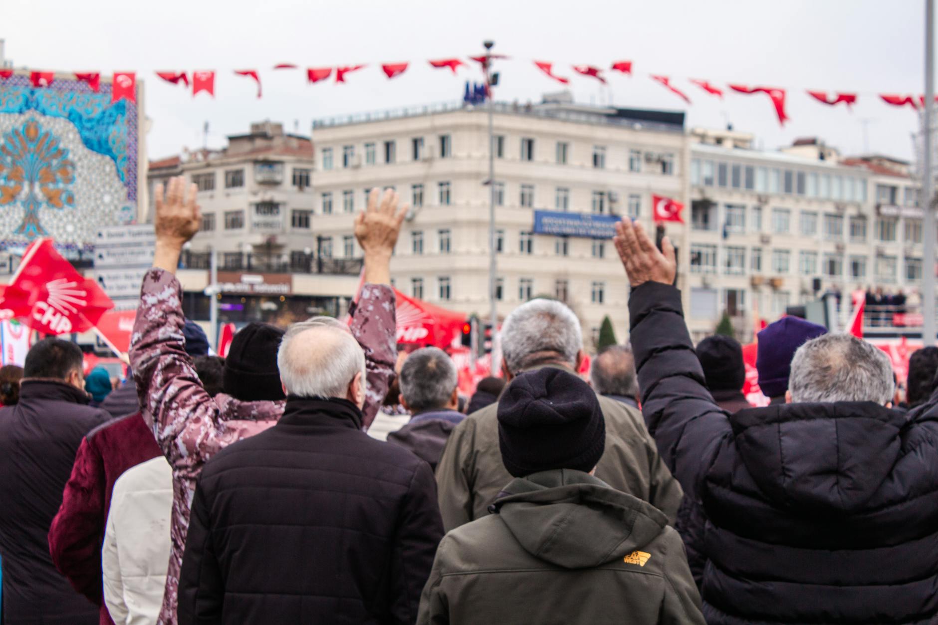 Crowd at a public rally with flags raised, focusing on community spirit and engagement.