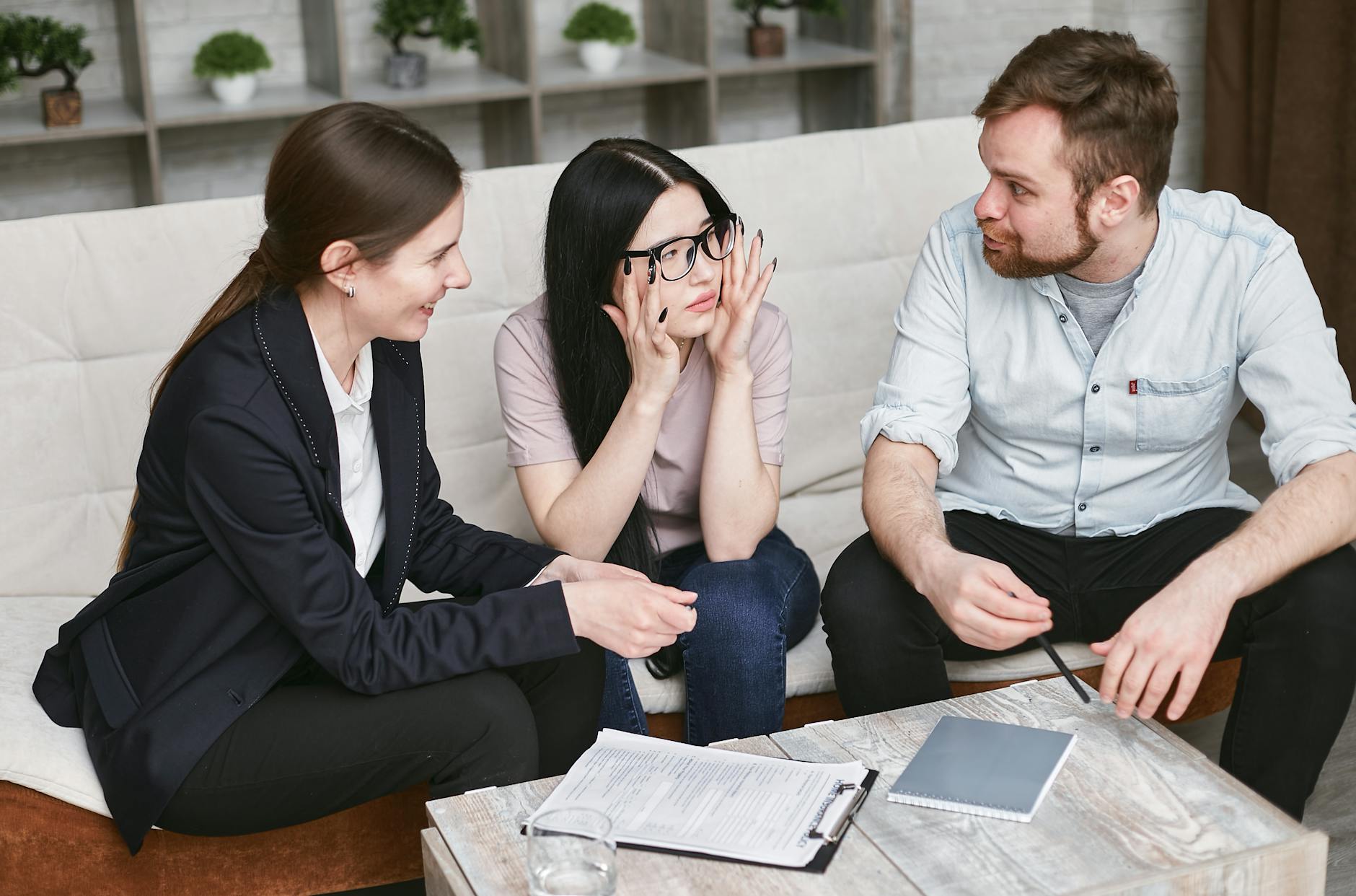 Three adults discussing documents and plans during a collaborative business meeting indoors.